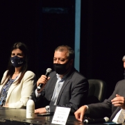 Secretário Ronaldo Nogueira falando ao microfone, ao lado uma mulher vestida de blazer branco e um senhor de terno e gravata.